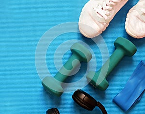 Sport fitness concept, space for text, black sneakers, blue dumbbells, headphones, fitness jump rope template