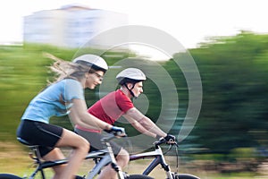 Sport and Fitness Concepts and Ideas: Young Caucasian Couple Having a Sppedy Bicycle Trip Outdoors. Blurred Motion Due to Paning.
