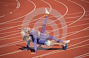 sport fitness couple training together stand in plank and do push up on outdoor stadium racetrack wearing sportswear