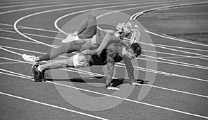 sport fitness couple training together stand in plank and do push up on outdoor stadium racetrack wearing sportswear
