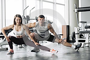 Sport, fitness, lifestyle and people concept - smiling man and woman stretching in gym