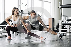 Sport, fitness, lifestyle and people concept - smiling man and woman stretching in gym photo