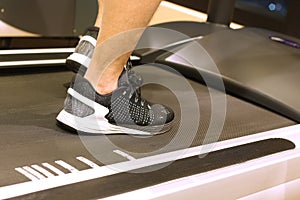 Sport, fitness, lifestyle, technology and people concept - close up of men legs walking on treadmills in gym
