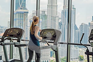 Sport, fitness, lifestyle, technology and people concept - woman exercising on treadmill in gym against the background