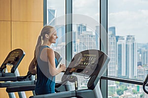 Sport, fitness, lifestyle, technology and people concept - woman exercising on treadmill in gym against the background