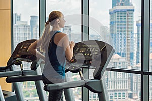 Sport, fitness, lifestyle, technology and people concept - woman exercising on treadmill in gym against the background of a big ci