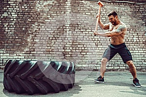 Sport Fitness Man Hitting Wheel Tire With Hammer Sledge Crossfit Training.