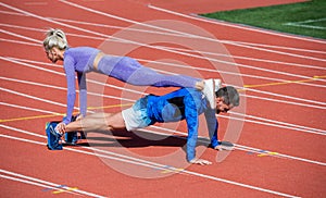 Sport fitness man and woman training together stand in plank and do push up on outdoor stadium racetrack wearing