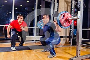 Sport, fitness, teamwork, bodybuilding people concept - man and personal trainer with barbell flexing muscles in gym