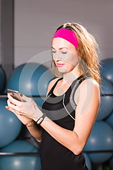 Sport, fitness, technology and people concept - young woman with activity tracker and smartphone in gym