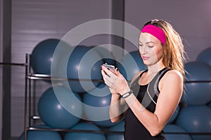 Sport, fitness, technology and people concept - young woman with activity tracker and smartphone in gym