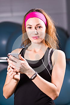 Sport, fitness, technology and people concept - young woman with activity tracker and smartphone in gym