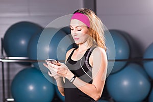 Sport, fitness, technology and people concept - young woman with activity tracker and smartphone in gym