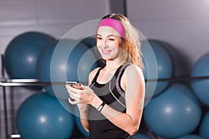 Sport, fitness, technology and people concept - young woman with activity tracker and smartphone in gym