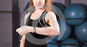 Sport, fitness, technology and people concept - young woman with activity tracker and smartphone in gym close-up