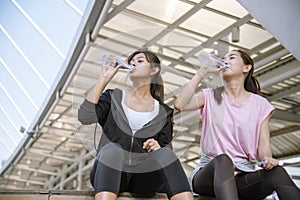 Sport Fitness Women drinking mineral water after running exercise modern city wear wellness sportswear outside. Young woman