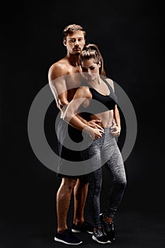 Sport, fitness, workout concept. Fit couple, strong muscular man and slim woman posing on a black background