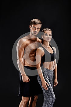 Sport, fitness, workout concept. Fit couple, strong muscular man and slim woman posing on a black background