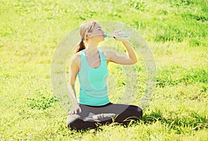 Šport vhodnosť jóga žena na tráva a pitie voda fľaša v lete 