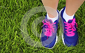 Sport Footwear on Female Feet on Green Grass. Closeup