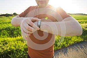 Sport, gadget, activity tracker and people concept - Close up of runner jogging outside looking at his wearable fitness