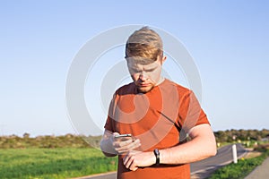 Sport, gadget, activity tracker and people concept - Male runner jogging outside looking at his wearable fitness