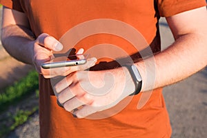 Sport, gadget, activity tracker and people concept - Male runner jogging outside looking at his wearable fitness