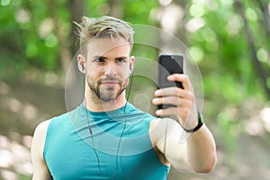 Sport gadget concept. Athlete mobile phone set up playlist before runnig. Man athlete busy face setting up smartphone photo