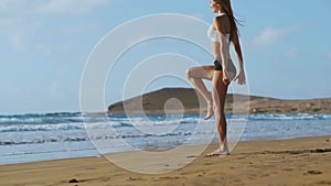 Sport girl on a beach doing lunges exercises. Concept of of a healthy lifestyle