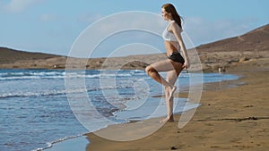 Sport girl on a beach doing lunges exercises. Concept of of a healthy lifestyle