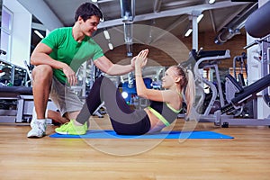 Sport girl doing abs exercises with a trainer man on the floor a