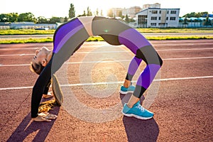 Sport girl engaged in a warm-up at the stadium at sunset