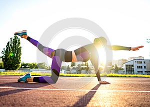 Sport girl engaged in a warm-up at the stadium at sunset