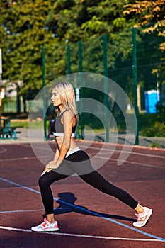 Sport girl. The girl is doing fitness exercises. Beautiful young sports woman doing exercises. A girl is training on a sports fiel
