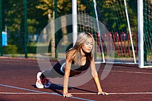 Sport girl. The girl is doing fitness exercises. Beautiful young sports woman doing exercises. A girl is training on a sports fiel