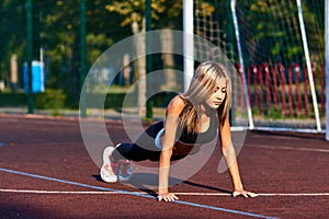 Sport girl. The girl is doing fitness exercises. Beautiful young sports woman doing exercises. A woman is training on a sports fie