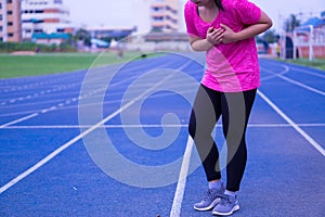 Sport girl having heart attack or chest pain after jogging or running work out on running track. Sport and Health care concept