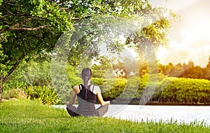 Sport girl meditating in nature green park at the sunrise