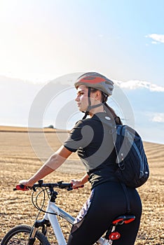 Sport girl on a mountain bike in the field side view