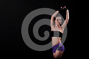 Sport girl pulls hands to the top of black background.