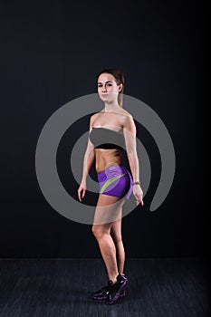Sport girl stands and stares at camera against black background.