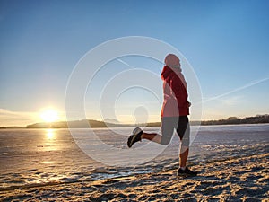 Sport girl in winter clothes running away to horizon of icy sea