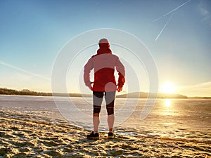 Sport girl in winter clothes running away to horizon of icy sea