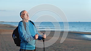 Sport grandfather backpacker Scandinavian walking stick contemplate sea beach sunset enjoy break