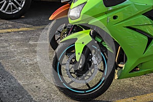 sport green bike parked. parking background. sports motorcycle with aluminum frame. shock absorber fork and brake disc on the