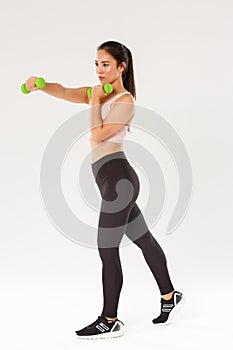Sport, gym and healthy body concept. Full length of focused female athelte, asian brunette girl doing fitness exercises
