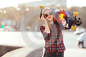 Sport happy girl posing in summer with skateboard. Stylish lucky hipster woman with colorful longboard in sunset in
