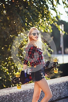 Sport happy girl posing in summer with skateboard. Stylish lucky hipster woman with colorful longboard in sunset in