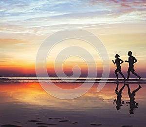 Runners on the beach, silhouette of people jogging at sunset, healthy lifestyle photo