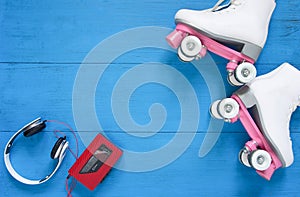 Sport, healthy lifestyle, roller skating background. White roller skates, headphones and vintage tape player. Flat lay, top view.